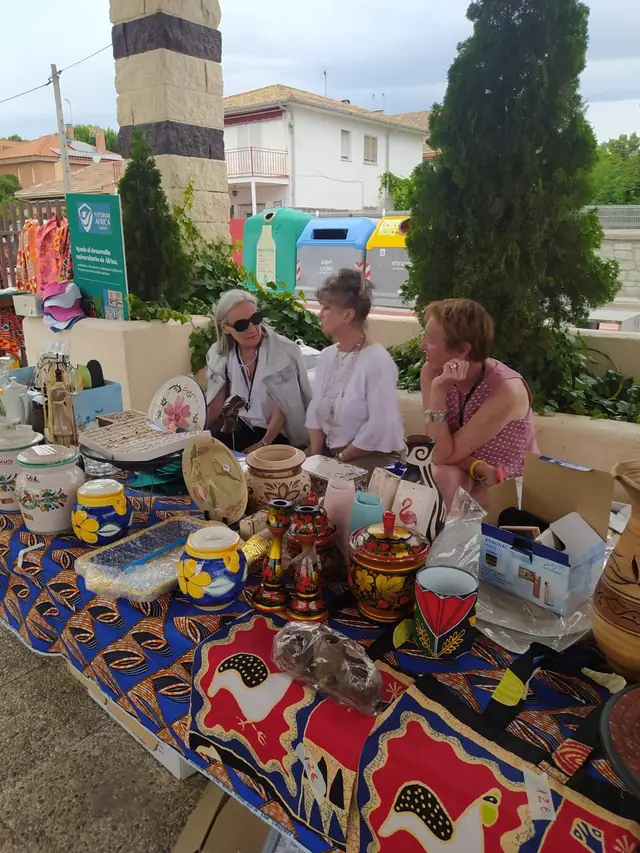 Colaboradoras de AUDE junto a un puesto de cerámica y telas