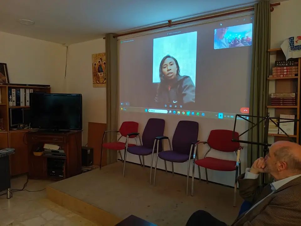 Adelphine en videollamada proyectada en la sala