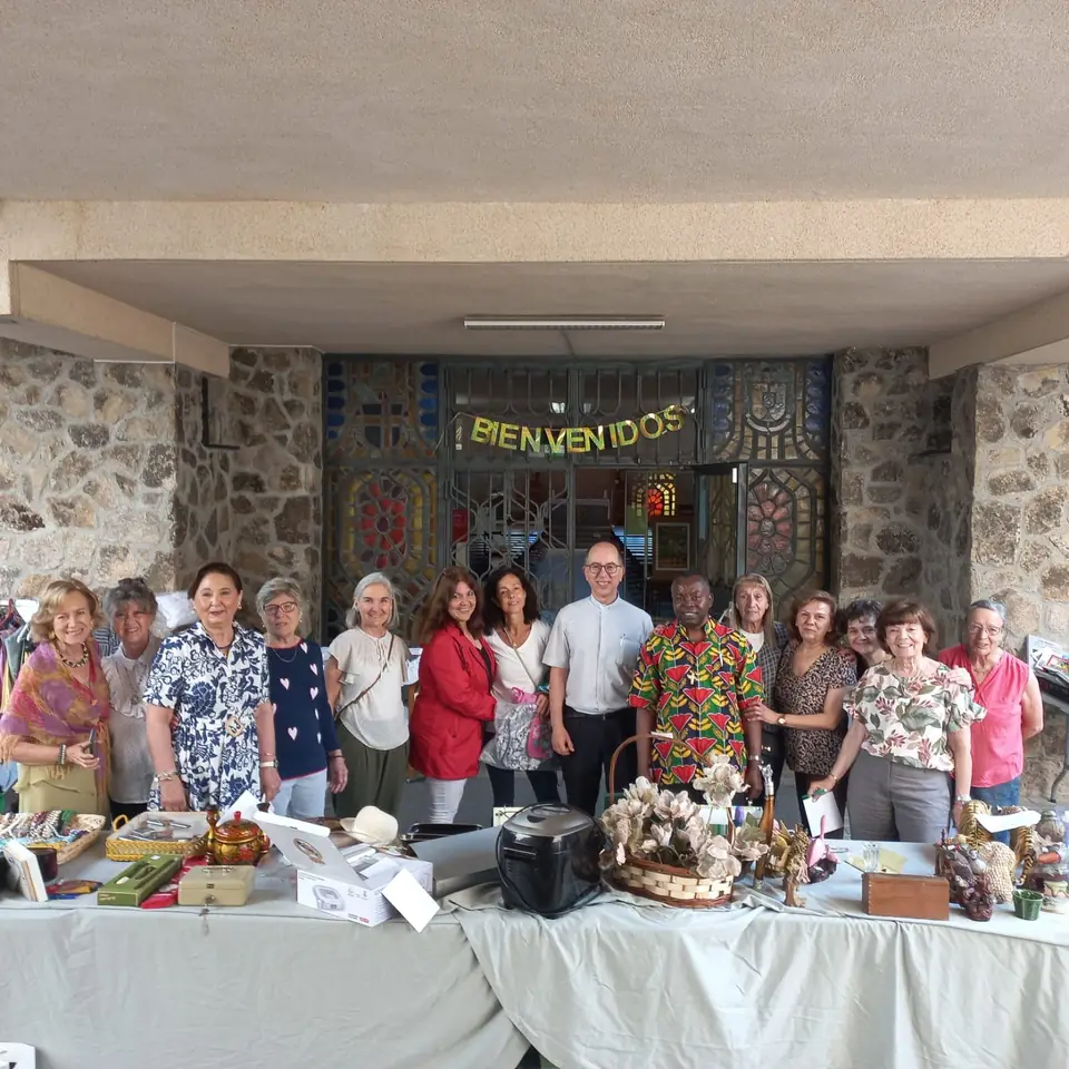 Colaboradores de AUDE junto a las mesas del mercadillo solidario