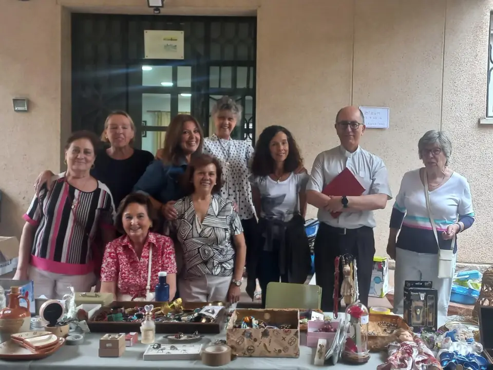 Colaboradores de AUDE junto a las mesas del mercadillo solidario