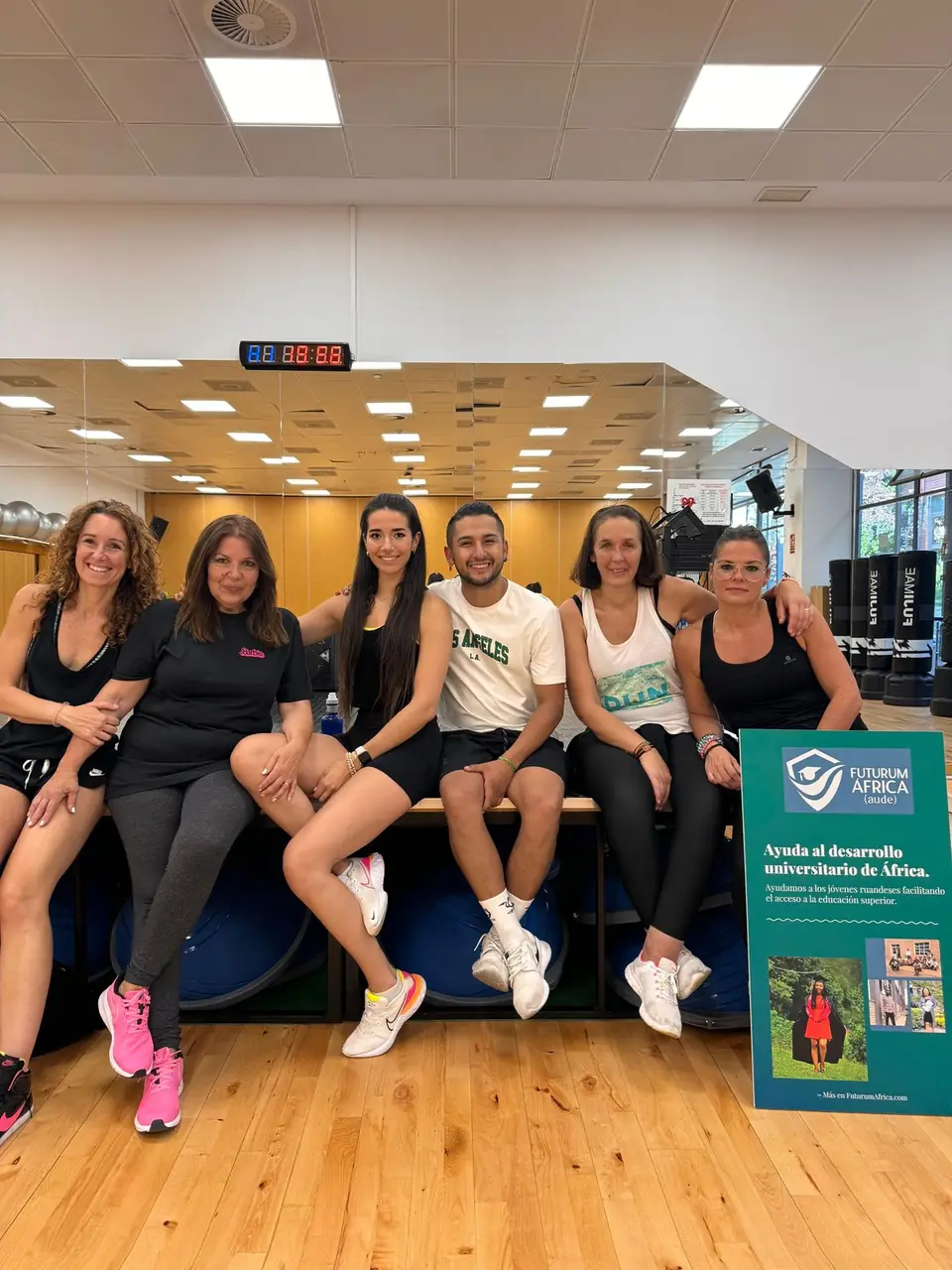 Participantes de la clase de zumba solidaria junto al cartel de AUDE